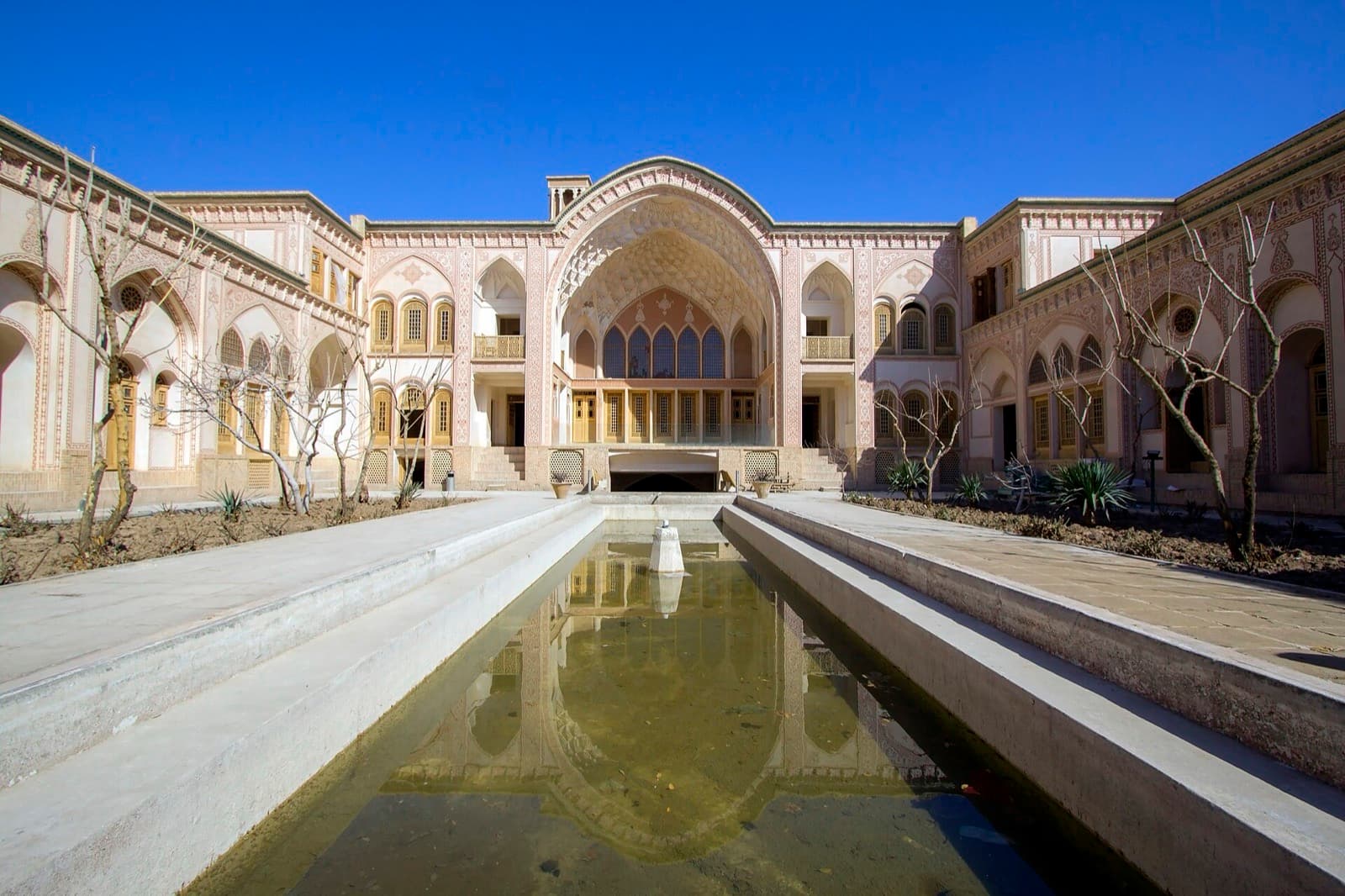 حوض بلند حیاط و نمای ایوان اصلی خانه عامری‌ها زیر آسمان آبی