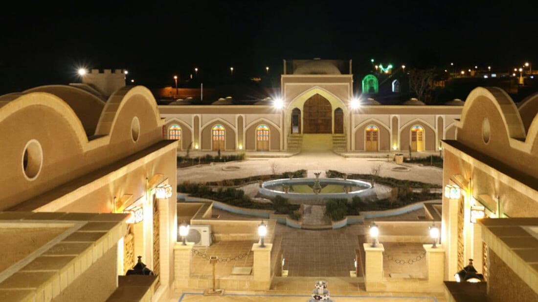 حیاط هتل یلو در شب با حوض و نورپردازی ایوان‌ها
